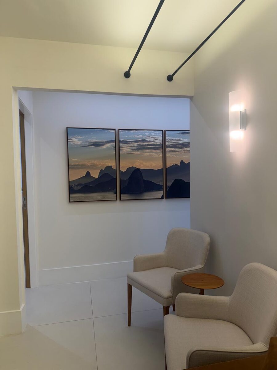 Sala de espera do consultório da Dra. Jéssica Miari em Ipanema, com poltronas e um quadro da paisagem do Rio de Janeiro